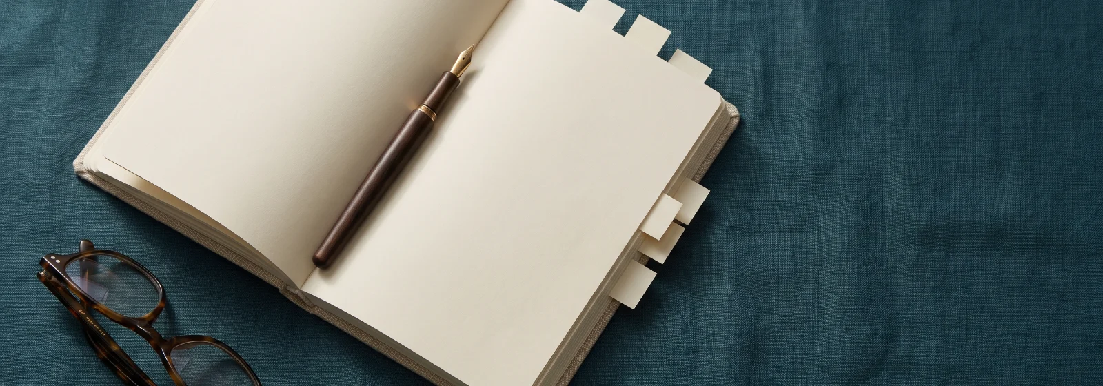Carnet ouvert aux pages vierges avec onglets de papier, stylo plume et lunettes